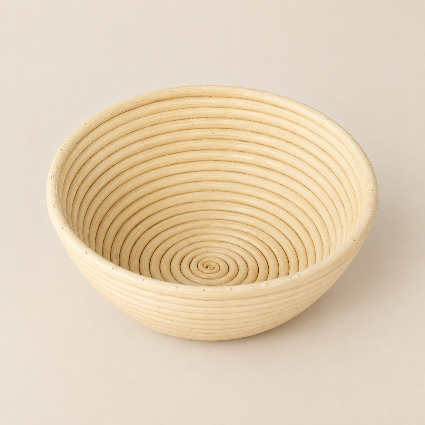 Banneton rond de couleur claire, avec nervures en spirale.